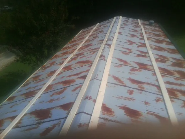 Rusted metal roof panels with new wood purlins before replacement — Storm Damage Roof Repair in West Branch by Roofing Brothers