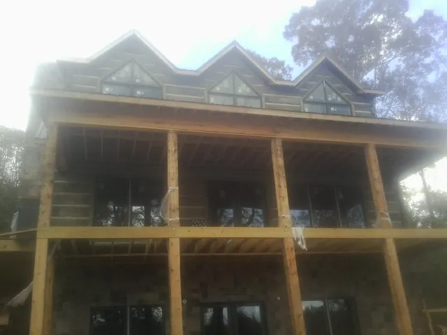Dormers and porch framing on a large log home under construction — Roof Coating work by our crew in West Branch