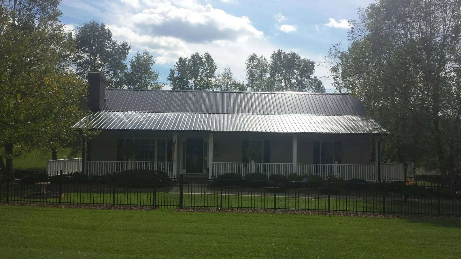 Gray metal roof on a brick ranch with a full width front porch — Gutter Guard Installation work by our crew in West Branch